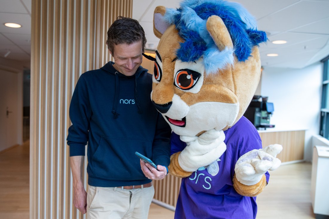 Alexander Rein, COO i Nors Care, viser Toppseriens maskot, Toppsi, hvordan man bruker Nørs-appen.